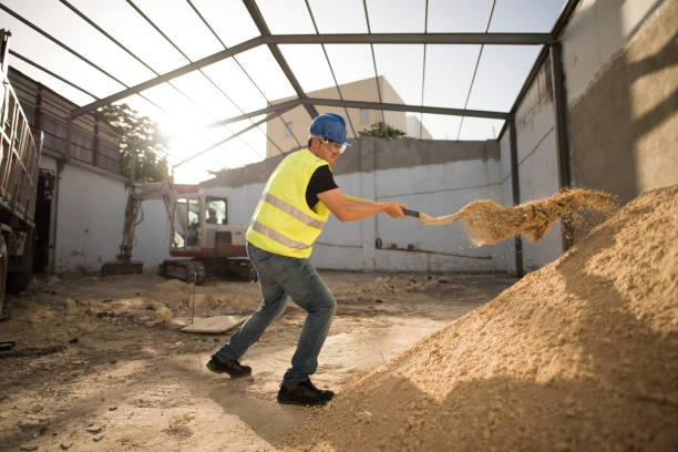 Construction worker with a shovel moves the sand so that it is less compact and looser and make the mixture in the concrete mixer stock photo
