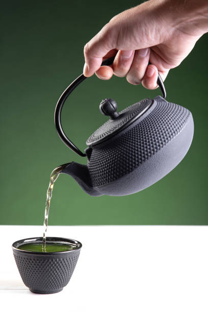 istock Water poured into a dark cup of green tea on  green background with copy space.Vertical format. 1317145773