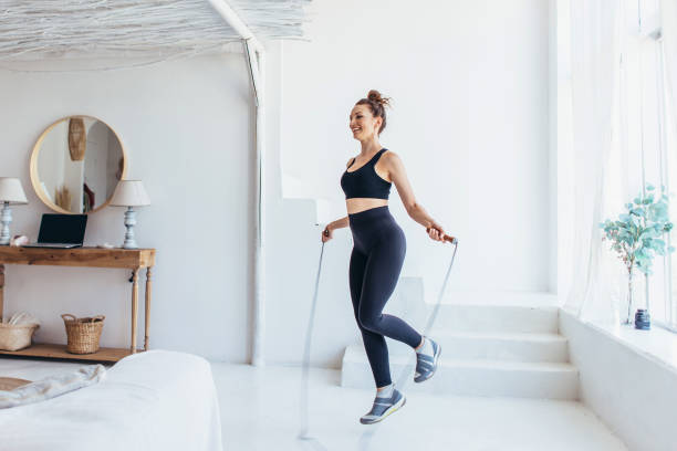 mujer en forma con cuerda de salto en casa haciendo saltar el entrenamiento. - saltar actividad física fotografías e imágenes de stock