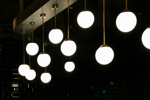 A contemporary chandelier featuring an intricate, abstract design with glowing bulbs. The elegant fixture hangs from a cathedral ceiling, casting a sophisticated and modern ambiance.