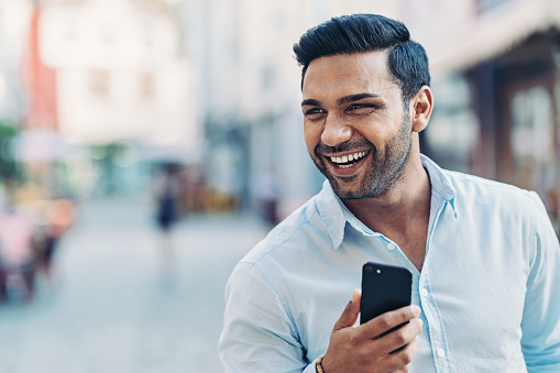 Smiling young man holding cell phone