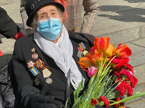 Kiev Ukraine-09 May 2021: An elderly woman veteran at the May 9 celebration. Honorable lady with numerous medals and flowers.