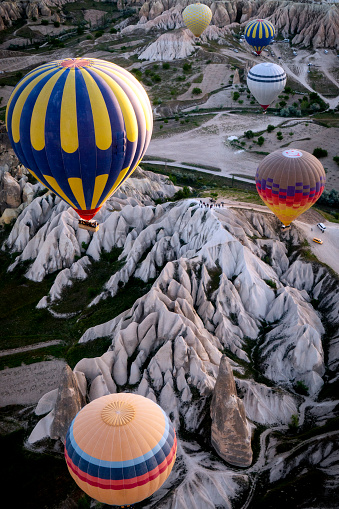 Grub of colorful hot air balloon flying over Cappadocia which is a very famous and touristic place. The hot air balloon flying over the rocks and houses. The air is clean.