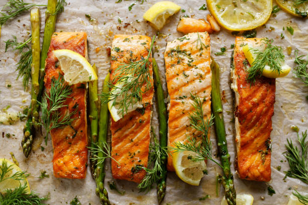 salmón al horno con hierbas aromáticas y limón en papel de hornear - baked salmon fotografías e imágenes de stock