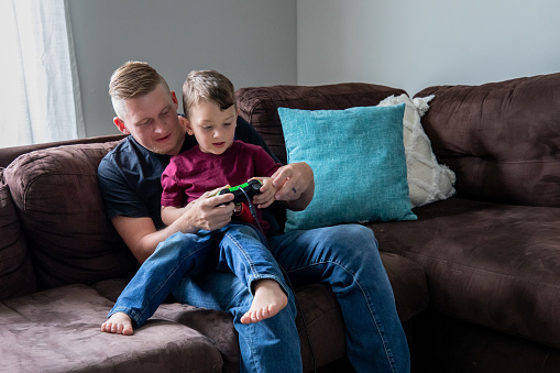 Father teaches his young son to play video games