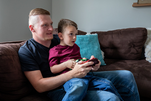 Father teaches his young son to play video games