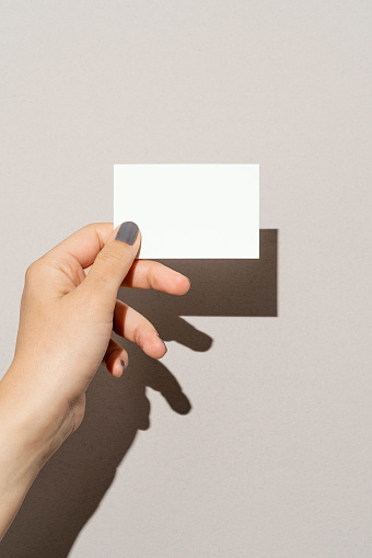 Hand holding blank white business card on white background