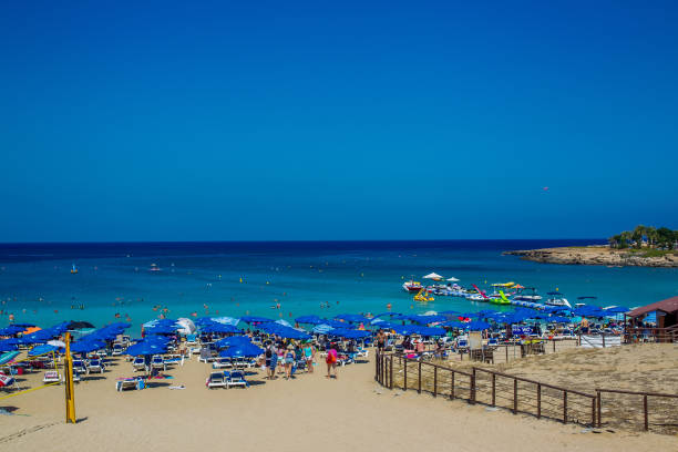 istock Amazing   Protaras beach  ( Fig tree bay)  next to Protaras in august - Mediterranean  resort!  Unrecognizable persons. A person paragliding - small point in sky. Paragliding person - small point in sky 1317166364