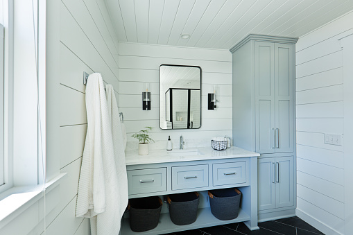 A contemporary modern bathroom design for a country home cabin. featuring a  classic freestanding vanity and linen storage cabinet.