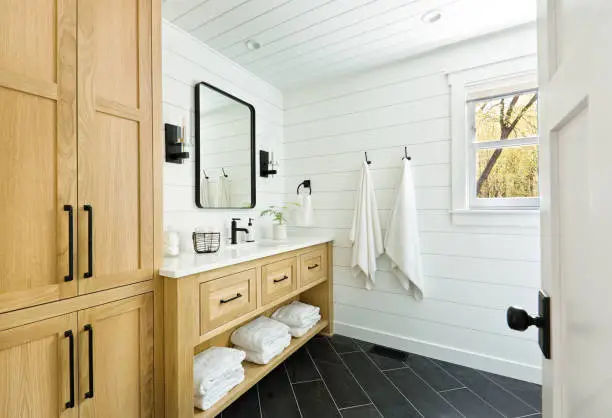 A contemporary modern bathroom design for a country home cabin. featuring a  classic freestanding vanity and linen storage cabinet.