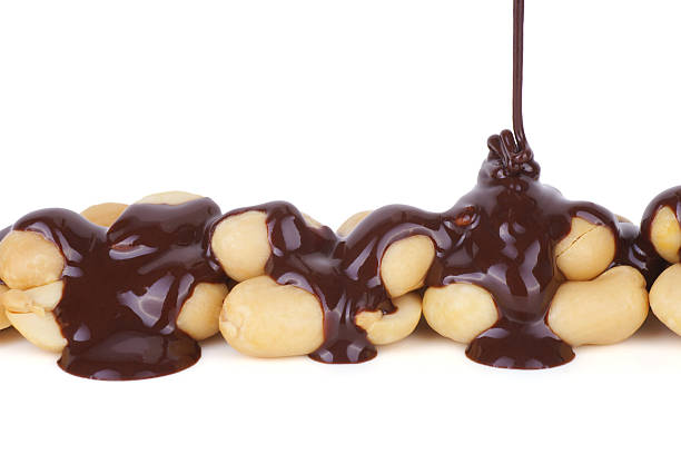 geschmolzener schokolade eingießen auf erdnüsse - chocolate chocolate candy dark chocolate pouring stock-fotos und bilder