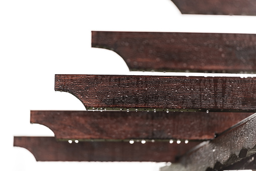 Pergola roof close-up. Individual elements of a wooden roof with raindrops. Brown beams and water droplets hanging down.
