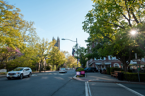 Princeton, USA - May 1, 2021. Traffic on street with people walking on sidewalk in downtown Princeton, New Jersey, USA.