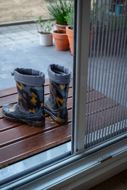 istock Dirty boots in front of a mosquito wire door. 1317182356