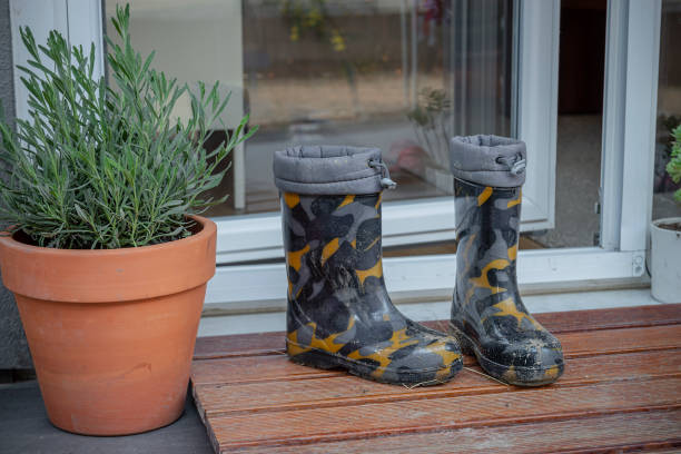 Image with red and green rubber boots, a lavender flowerbed and a wooden wall