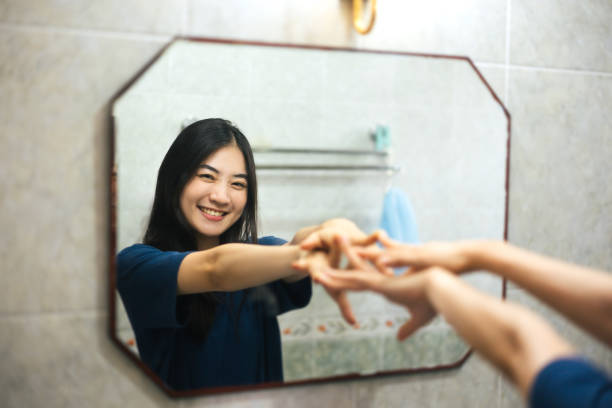 Young adult smile asian woman practice self talk conversation with mirror. Young adult smile asian woman practice self talk conversation with mirror. Mental health in bathroom at home. Healthy lifestyle after wake up life with satisfaction concept. toilet photos stock pictures, royalty-free photos & images