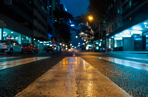 Photo of Brisbane city streets just after a rainstorm, wet bitumen/concrete with streetlights, car headlights and building lights reflections, night time, evening, midnight.