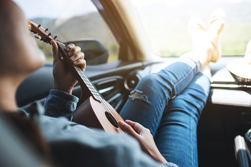 A woman playing Ukulele while laying in the car