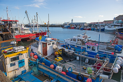 Landscape panorama view of coastal seaside town harbor port with fishing boats moored up on dock