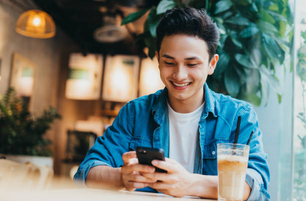 Man lifestyle Young Asian man sitting and using smartphone at coffee shop only men stock pictures, royalty-free photos & images