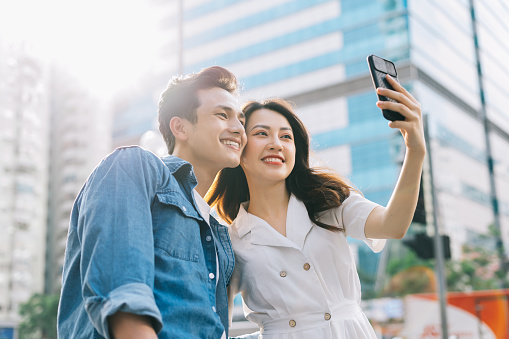 Young Asian couple taking selfie together on the street