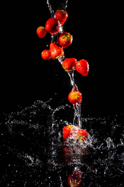 istock Strawberries falling in water on black background 1317205740