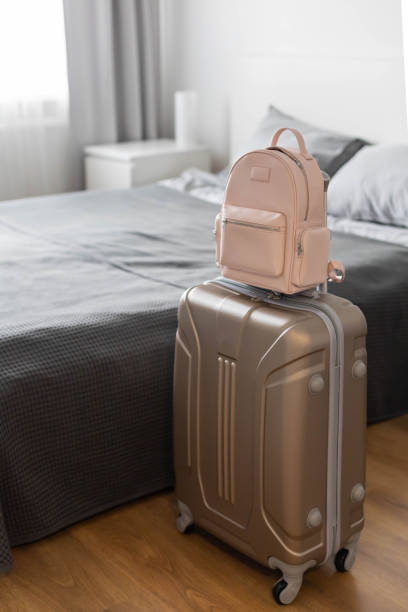 istock Modern suitcase full of things, handbag and straw hat. Baggage case packing getting ready to travel 1317205974