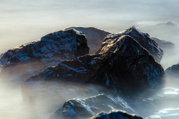 Photo of Seascape, water rolling over rocks at coastline mist long exposure scenic background.