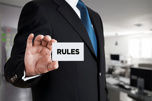 Businessman shows a business card with the word rules. Business rules, legal standards or policy guidelines concept.