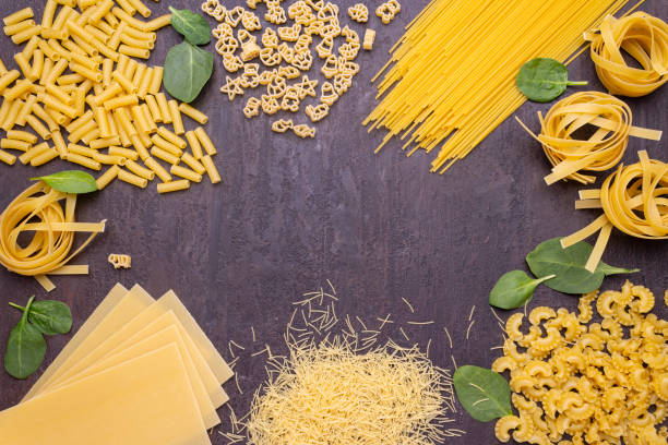 istock Various types of pasta and spinach leaves on a stone countertop. 1317210789
