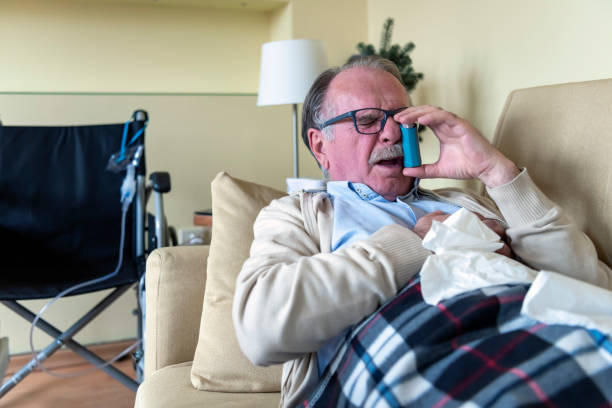 istock Senior Man with Asthma is Lying in the Bed and Using an Inhaler. 1317211462