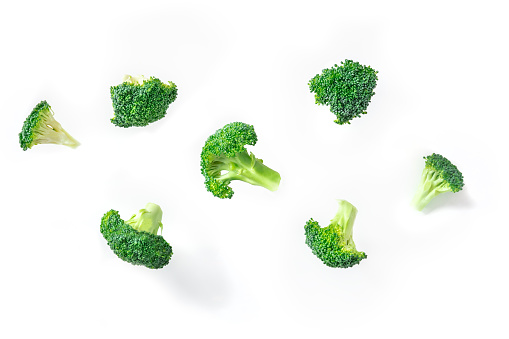 Broccoli florets flying on a white background. The concept of a healthy vegan diet with floating pieces of vibrant green broccoli