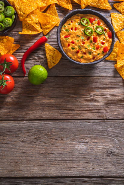 istock cheedar cheese dip sauce with Nacho chips with tomato and chili on a rustic wooden table 1317218823