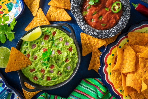 istock Guacamole avocado sauce and Mexican tomato salsa dip with nacho chips on blue 1317218884