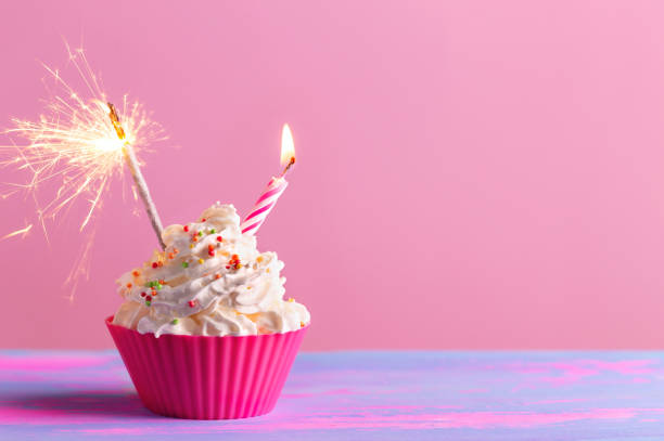 istock Birthday cake cupcake with candle, sparkler on pink background 1317220167