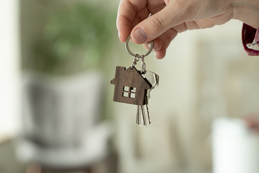 Close-up of a woman's hands holding the keys to a new house, a woman moves into a new apartment.