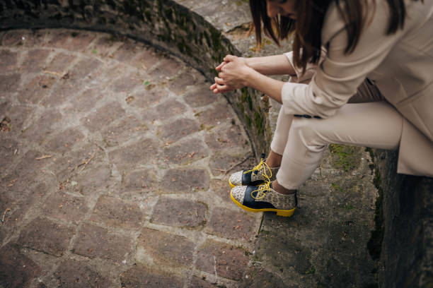 One woman, female in modern clothing sitting outdoors on concrete bench.
