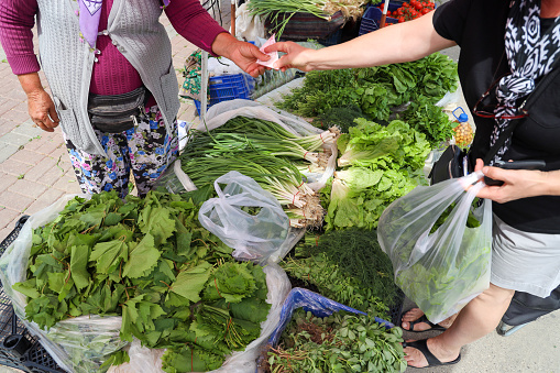 Woman buying fresh organic green vegetables at the village bazaar market in Asia.