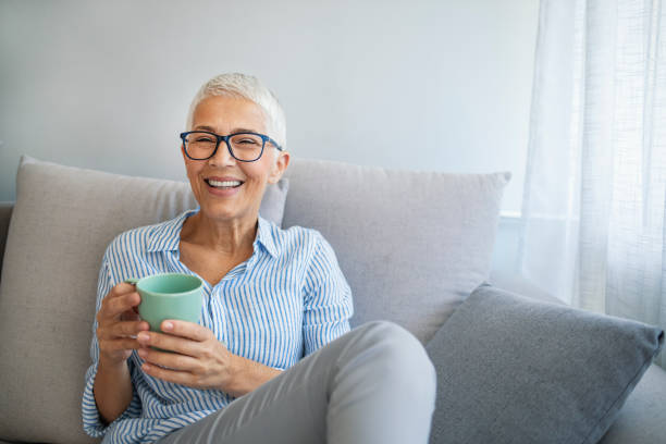 istock Senior woman drinking hot drink sitting on sofa 1317233076