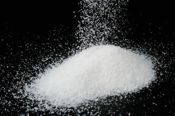 istock White granulated sugar drips onto the black 1317235622