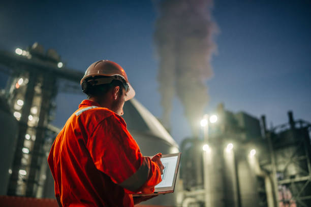 engenheiro com laptop trabalhando em refinaria de petróleo - chemical plant fotos - fotografias e filmes do acervo