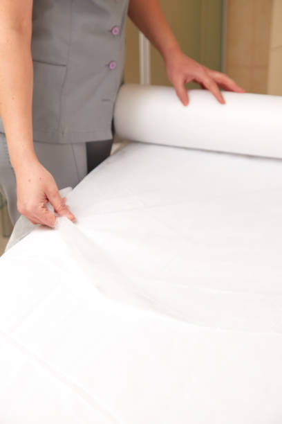 istock Woman massage therapist spreading disposable sheet on massage table 1317237335