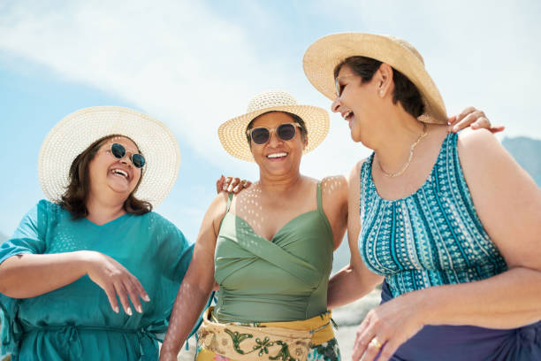 shot of a mature group of friends standing together during a day out on the beach - recreational pursuit carefree nature vacations imagens e fotografias de stock