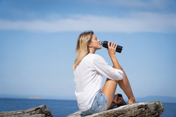 woman sitted on rocky cliff in front of the blue sea - sea zen like landscape water imagens e fotografias de stock