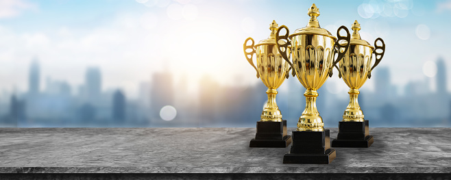 1st champion award, the best prize and winner concept, championship cup or winner trophy on wood table with soft blue and bokeh city background