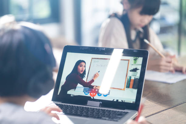 istock Homeschool Asian little young boy learning online class from school teacher by digital remote internet meeting due to coronavirus pandemic. Kid looking computer laptop screen that woman teaching. 1317246541