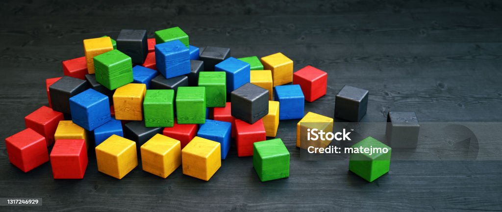 A pile of colorful wooden cube blocks laid out on a dark wooden surface Puzzle Stock Photo