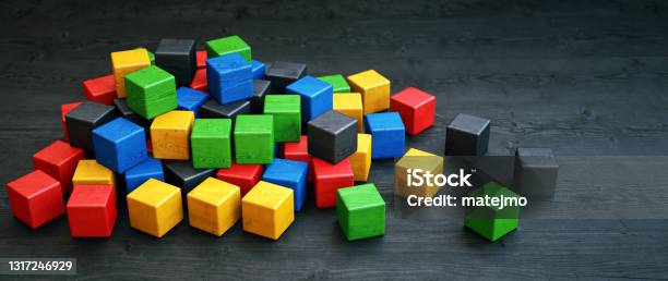 A Pile Of Colorful Wooden Cube Blocks Laid Out On A Dark Wooden Surface Stock Photo - Download Image Now