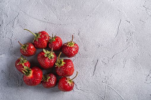 Fresh ripe strawberry fruits, summer vitamin berries on grey stone background, top view copy space