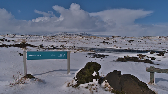 Vík í Mýrdal, Iceland - 03-28-2021: Rest area beside ring road (route 1) with information sign, volcanic rocks and beautiful view on the ice cap of Mýrdalsjökull glacier on sunny winter day.
